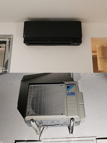 Photo d'un climatiseur daikin noir accroché au mur avec son moteur